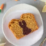 Veganer Osterhasenkuchen auf kleinem Teller, umringt von Mini-Möhrchen