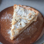 Marzipan Croissant Tarte mit Puderzucker auf kleinem Dessertteller